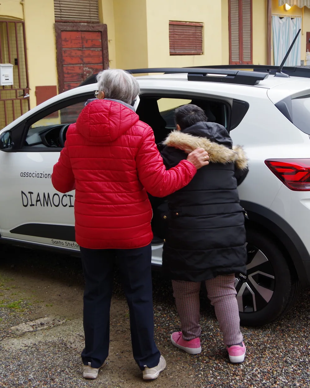 Una volontaria accompagna una signora verso l’auto dell’associazione